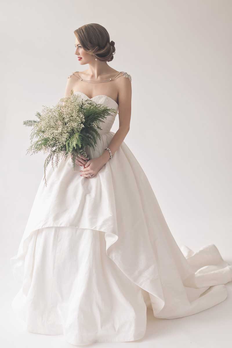 bride with low updo wearing ballgown and holding winter bridal bouquet