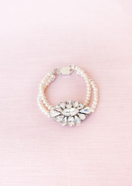 flat-lay of pearl and crystal brooch bracelet with two strands pearls