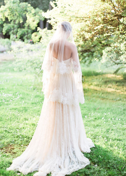 back view of bride in a garden wearing chantilly lace circular cut fingertip veil and lace dress.