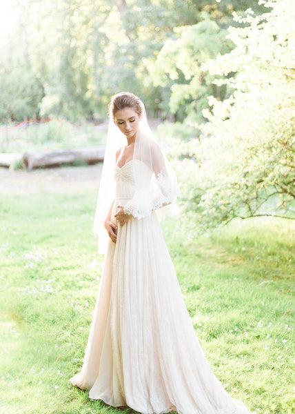 back view of bride in a garden wearing chantilly lace circular cut fingertip veil and lace dress.